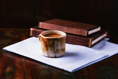 Cup of coffee and books on old wooden table, selective focus