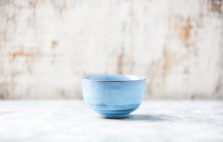 Blue ceramic bowl on a white wooden background. Selective focus.