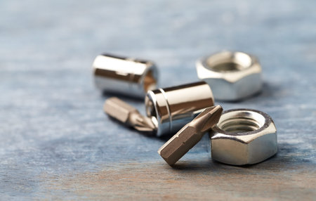 Set of metal nuts and bolts on rustic wooden background, closeup