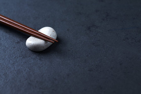 Chopsticks and white stone on black background. Space for text