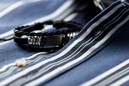 Close up of a man's blue striped shirt with a black belt