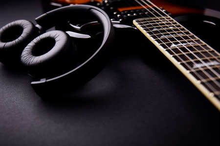 Guitar and headphones on a black background. Music concept.