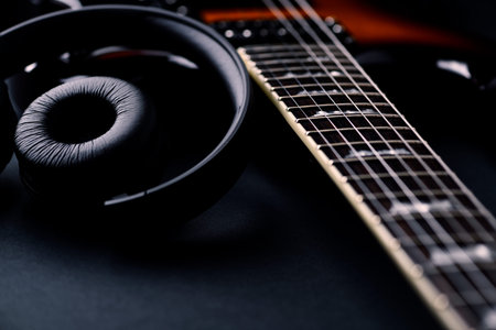 Headphones and electric guitar on a black background close-up.