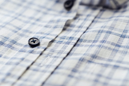 Closeup of blue checkered shirt with button on white background