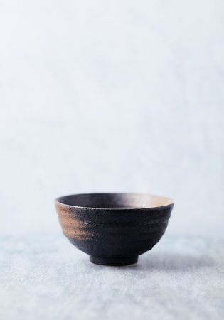 Empty ceramic bowl on grey background.