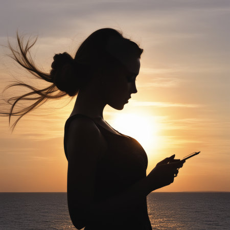 Woman with mobile phone at sunsetの素材