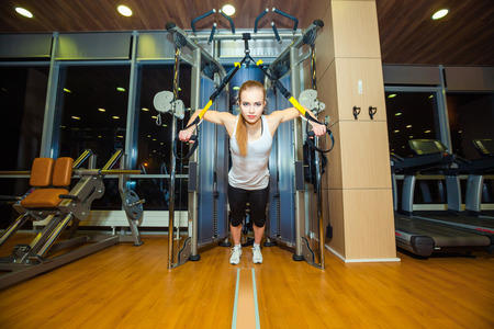 attractive woman does crossfit push ups with trx fitness straps in the gyms studioの写真素材