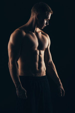 Close up of sports mans muscular back isolated on black backgroundの写真素材