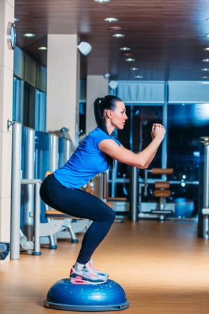 Woman making squats on balance trainerの写真素材