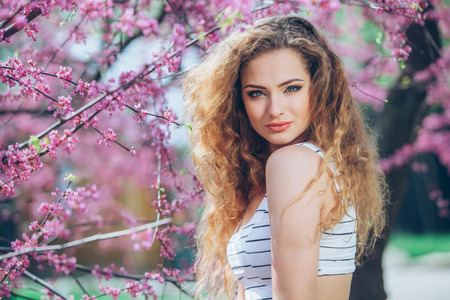 portrait of young lovely woman in spring flowersの写真素材