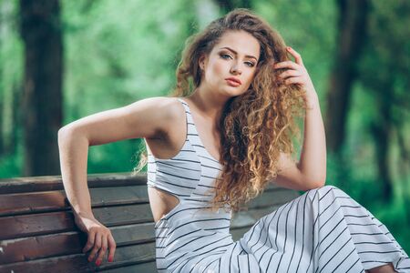 Beautiful young woman with gorgeous curly fair outdoorsの写真素材