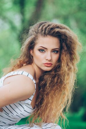Beautiful young woman with gorgeous curly fair outdoorsの写真素材