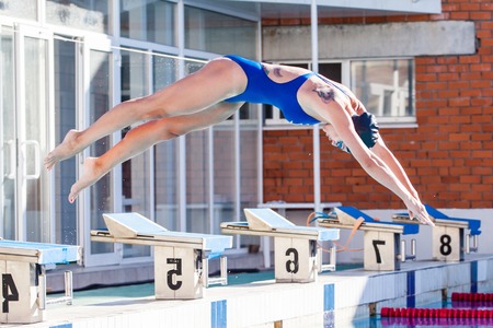 Portrait of a female swimmer, that wearing a swimming cap and goggles and preparing to jump into swimming pool. Sporty woman.の写真素材
