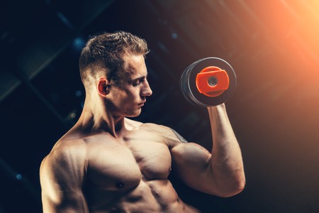 Athlete muscular bodybuilder training back with dumbbell  in the gym.の写真素材