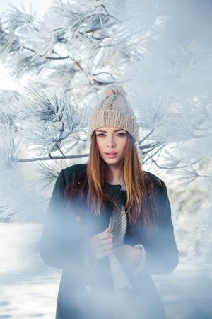 Beautiful winter portrait of young woman in the winter snowy scenery.