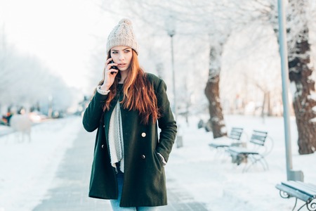 Young  woman smiling with smart phone and winter landscapeの写真素材