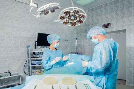 Surgeons team working with Monitoring of patient in surgical operating room for breast augmentation
