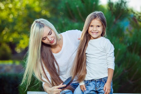 Woman brushing her daughter hair outdoorsの写真素材