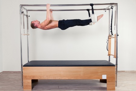 Pilates aerobic instructor man in cadillac fitness exercise.
