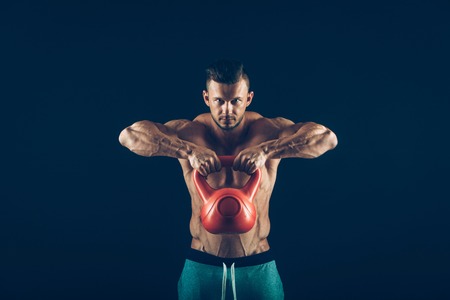 Fitness man doing a weight training by lifting a heavy kettlebell.の写真素材