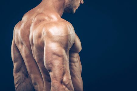 Strong athletic man back on dark background.の写真素材