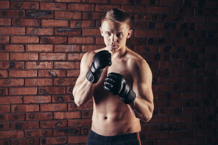 portrait of mma fighter in boxing pose against brick wall.