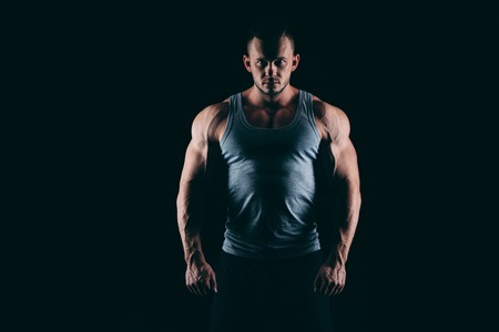Silhouette of a strong fighter. Confident young fitness man with strong hands and clenched fists....