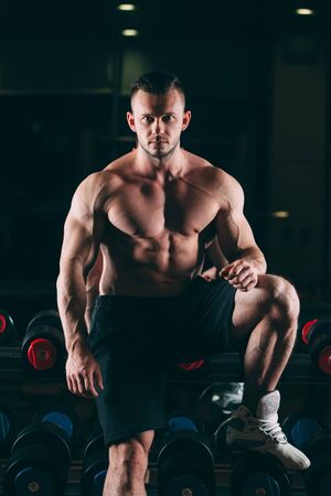 Muscular man out in gym standing near dumbbells , strong male naked torso abs.の写真素材