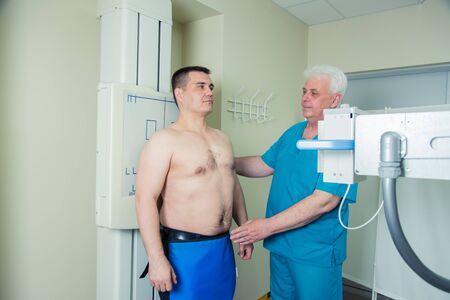 Mid adult men patient  mature male doctor setting up the machine to take x-ray
