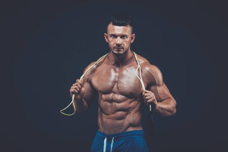 Muscular man skipping rope. Portrait of muscular young man exercising with jumping rope on black background. skipping  rope active  sport  fitnessの写真素材