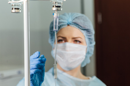 Female doctor adjusting infusion bottle in hospital.の写真素材