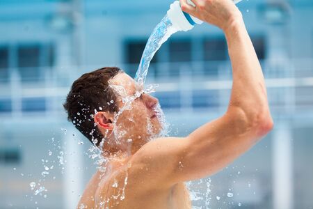 Man fitness runner drinking and splashing water in her faceの写真素材