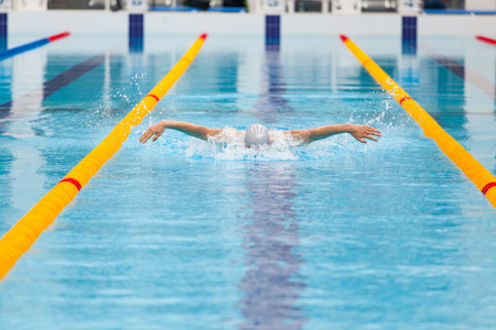 dynamic and fit swimmer in cap breathing performing the butterfly stroke.