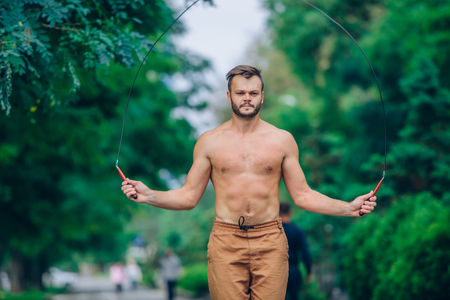 fitness, sport, training and lifestyle concept - healthy athlete bare-chested jumping with skipping rope outdoor.の写真素材