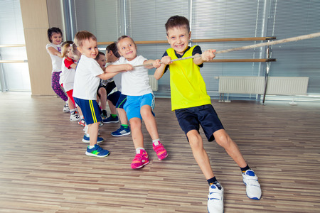 Group of kids pulling a rope in fitness room.の写真素材