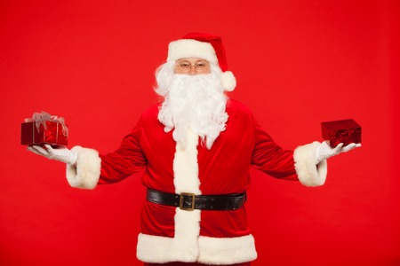 Photo of Santa Claus gloved hands holding red giftbox.の写真素材