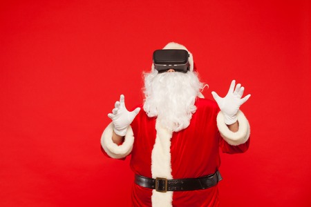 Santa Claus wearing virtual reality goggles, on a red background. Christmas.の写真素材
