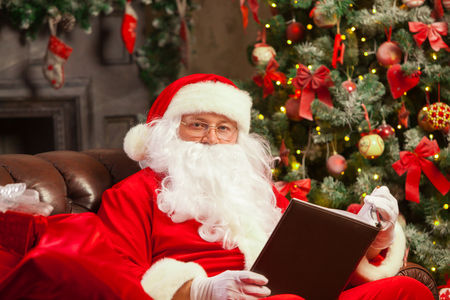Santa Claus sitting at his home in a comfortable chair and reading a letter. Christmasの写真素材