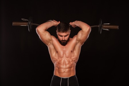 Muscular male athlete is training by lifting the barbell.の写真素材