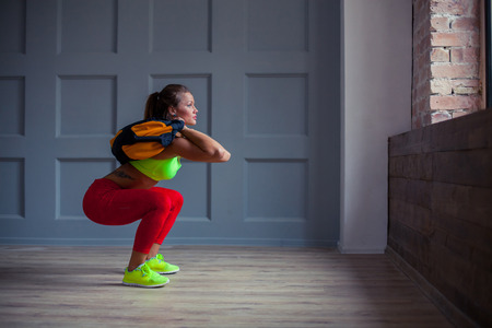 beautiful young woman is training with a sandbag in the gym.