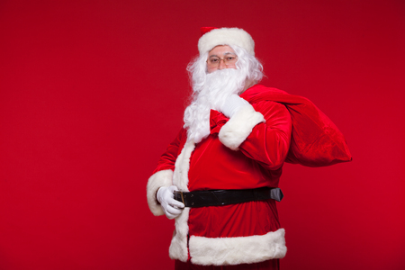 Christmas. santa claus with big bag on shoulder is on red backgroundの写真素材