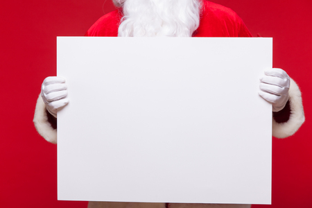 Santa Claus pointing in blank advertisement banner isolated on red background with copy spaceの写真素材