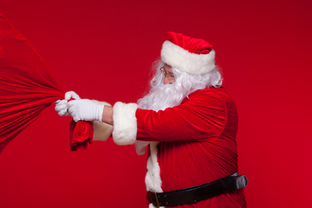 Christmas. santa claus with big bag on shoulder is on red backgroundの写真素材