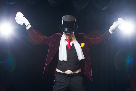 Midsection of magician showing fanned out cards against black background. Magician, Juggler man, Funny person, Black magic, Illusion Hands asideの写真素材