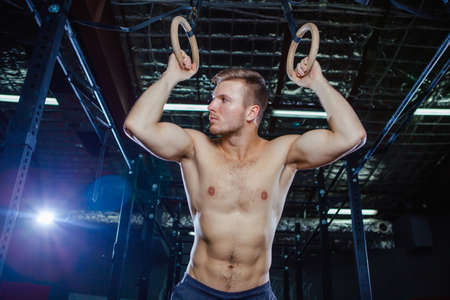 Muscular guy doing exercise on the rings Cross fit styleの写真素材