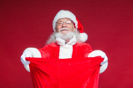 Christmas. Santa Claus in white gloves opened the bag with gifts and looks into it. Offers to take...