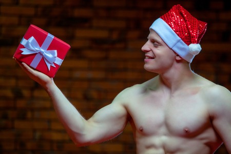 Santa Claus. Fitness Santa Claus isolated on the background of a brick wall. Sexy fitness santa claus. Muscular Santa Claus with giftboxesの写真素材