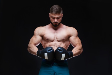 Strong muscular boxer in black boxing gloves. Isolated on black background.の写真素材