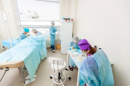 The doctor under the microscope recalculates the hair follicles. Baldness treatment. Hair transplant. Surgeons in the operating room carry out hair transplant surgery. Surgical technique that moves hair follicles from a part of the head.の写真素材