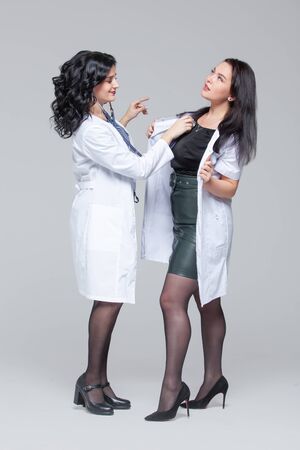 Female doctor examining another woman with stethoscopeの写真素材